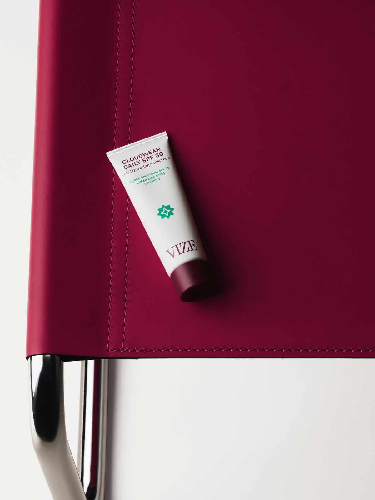 tube of cloudwear daily spf 30 on a burgundy chair with metal frame